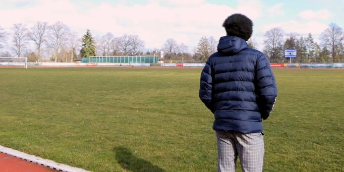 Kenny Abieba schaut auf einen leeren Fußballplatz.
