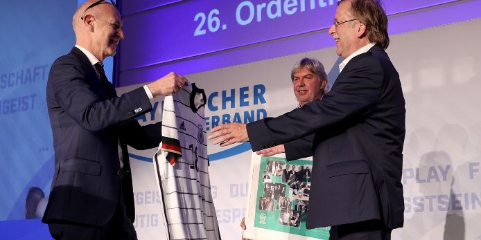 DFB-Präsident Bernd Neuendorf übergibt ein Geschenk an Rainer Koch. Im Hintergrund: Ronny Zimmermann.